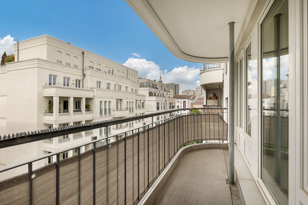 Moderner Balkon mit Metallgeländer und Blick auf benachbarte Wohnhäuser bei Tageslicht.