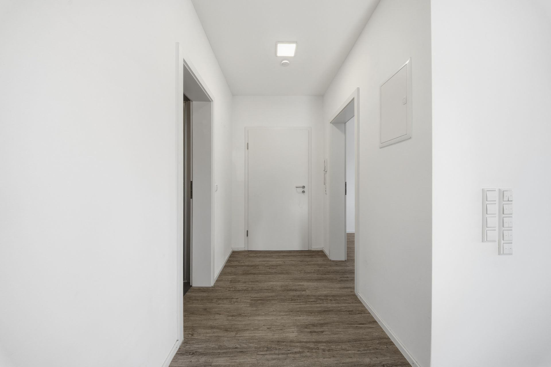 Heller Flur mit Holzboden und mehreren Türen in einer Wohnung.