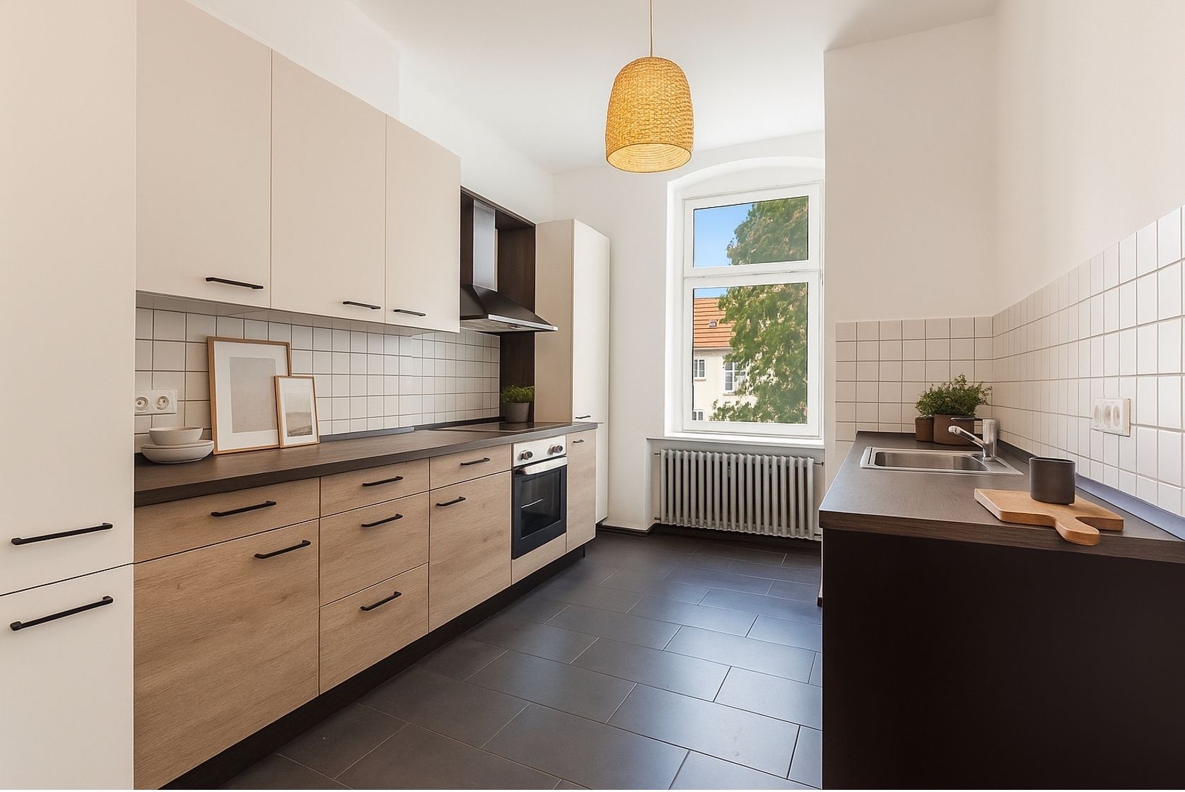 Moderne Küche mit Holzfronten, weißen Fliesen, großem Fenster und Hängelampe.