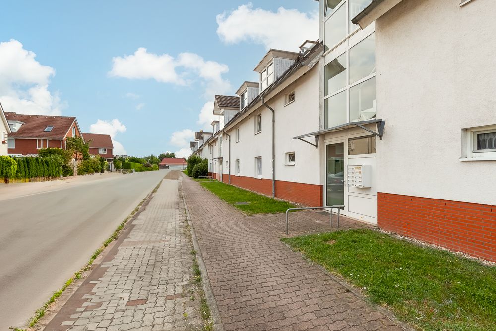 Eingang eines modernen Wohngebäudes mit Glasfassade an einer ruhigen Straße.