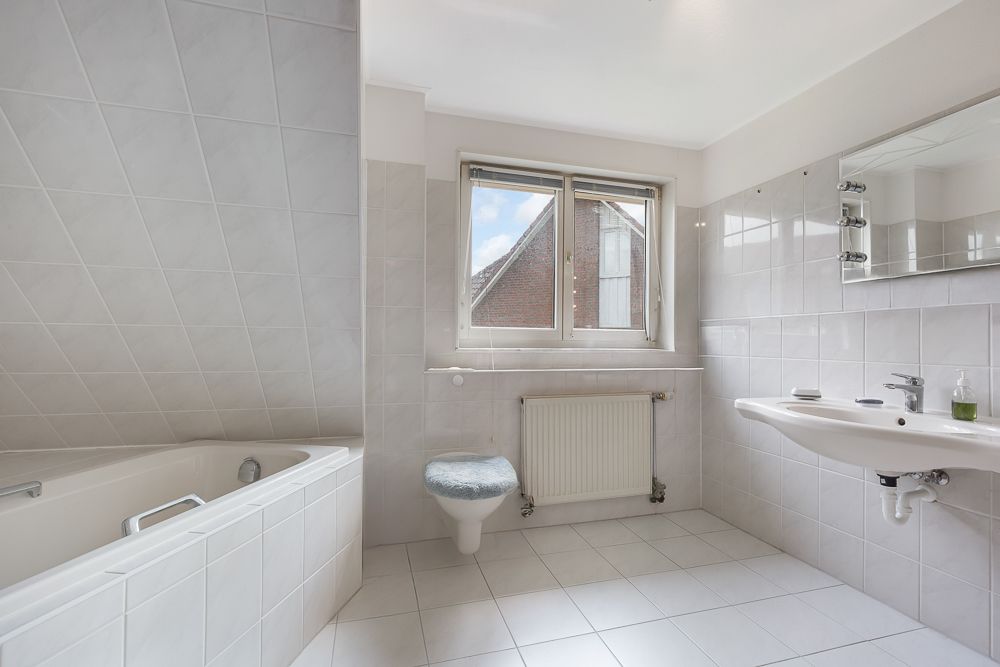 Helles Badezimmer mit Badewanne, Waschbecken, Toilette und Fenster.