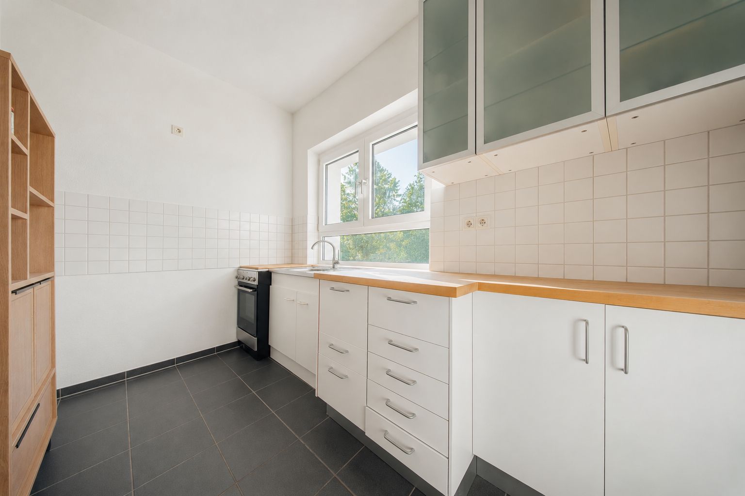 Helle Küche mit weißen Schränken, Holzarbeitsplatte und einem Fenster.