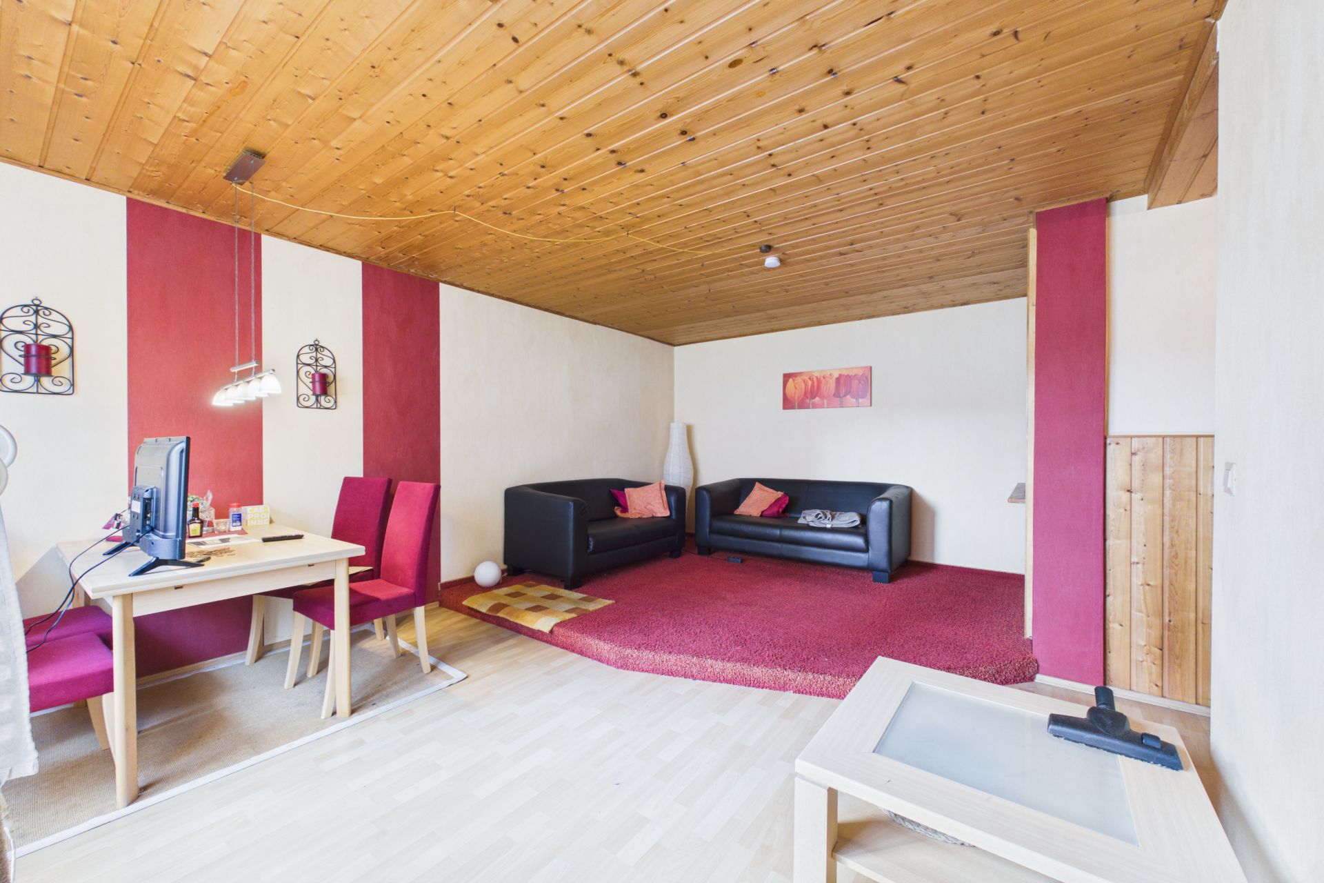 Helles Wohnzimmer mit Holzboden, zwei Sofas, Schreibtisch und rotem Teppich.