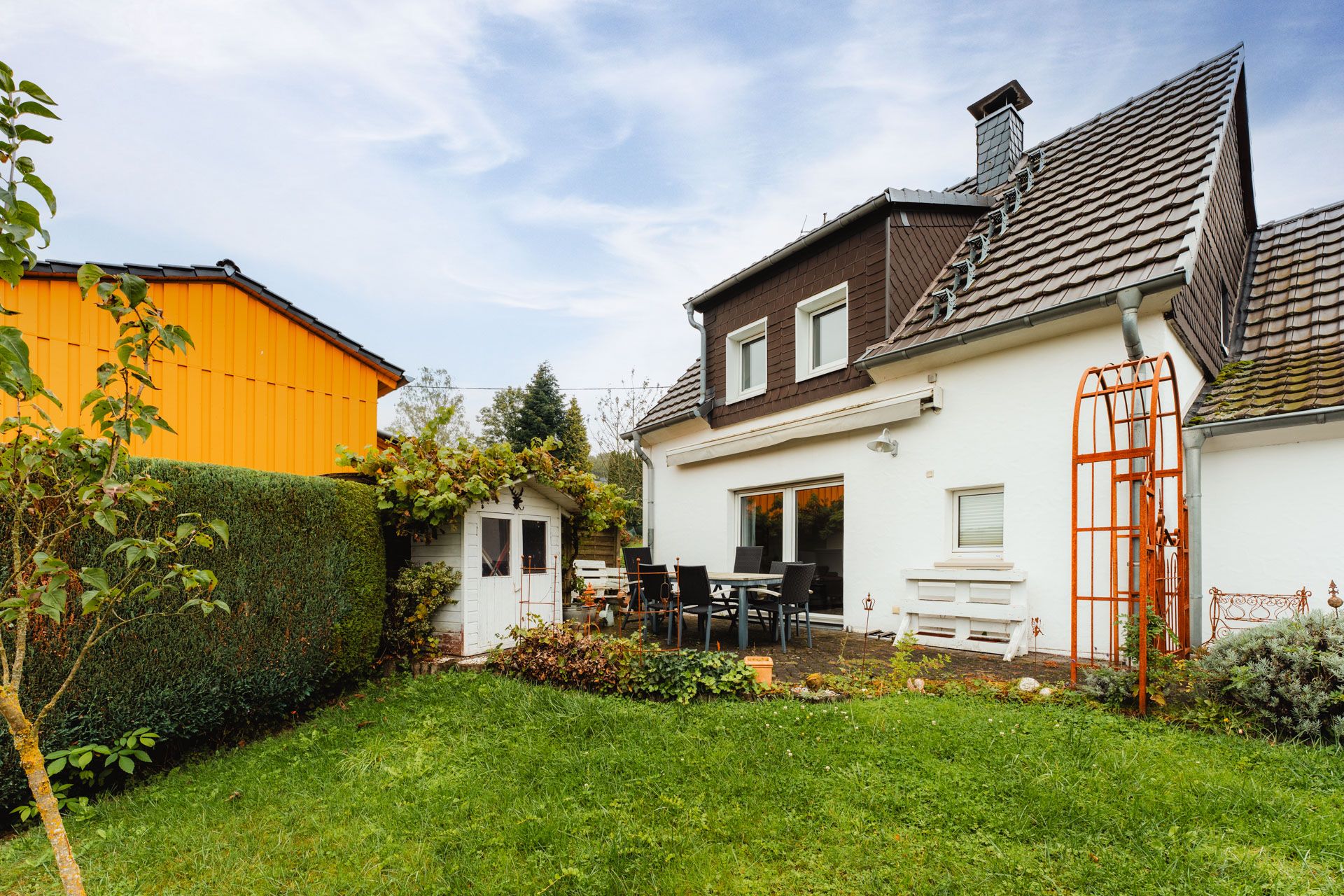 Haus mit Garten, Terrasse mit Sitzgruppe und kleinem weißen Gartenschuppen.