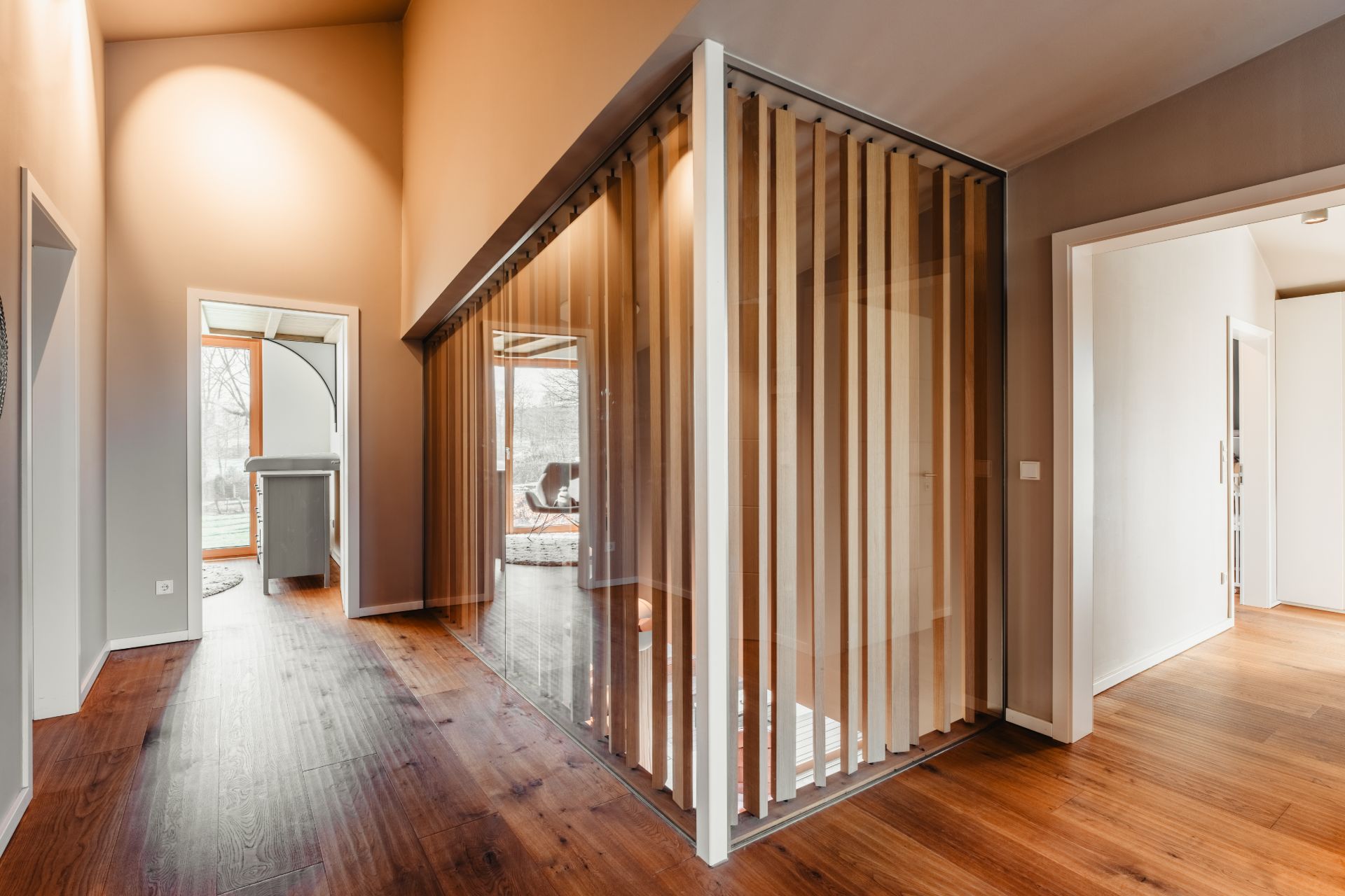 Moderner Flur mit Holzboden und abgetrenntem Raum mit Glaswänden und Holzlamellen.