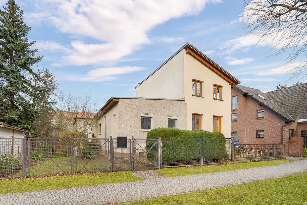 Zweistöckiges Wohnhaus mit Zaun, Gehweg und Rasen vor dem Haus.