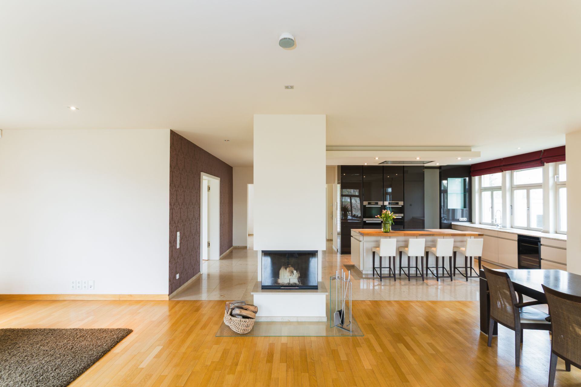 Helles Wohnzimmer mit Kamin, Holzboden, offener Küche und Esstisch.