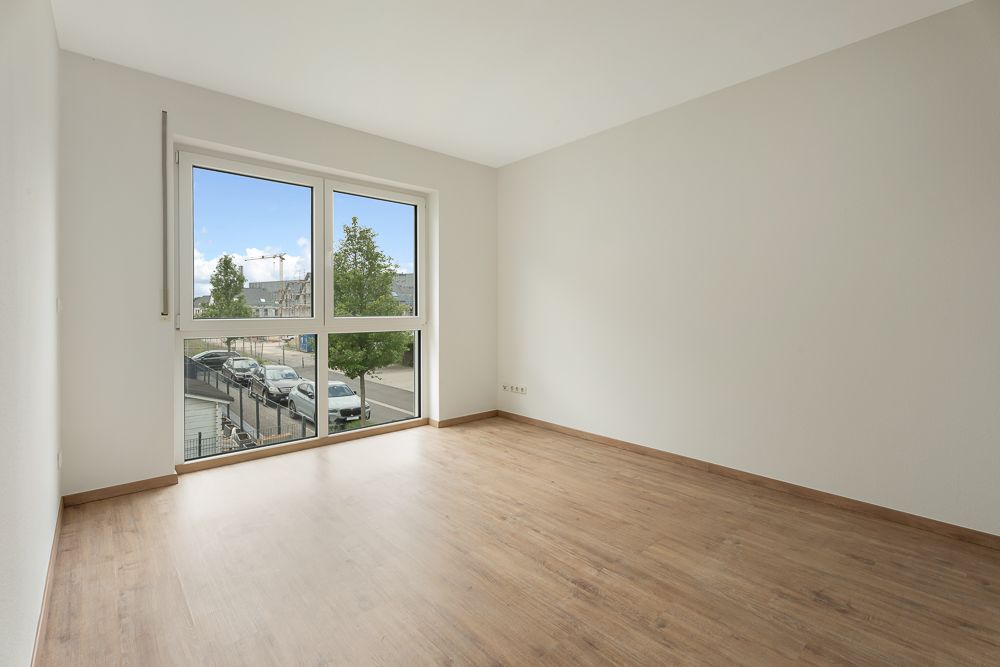 Leerer Raum mit Holzfußboden und großem Fenster mit Blick auf die Straße.