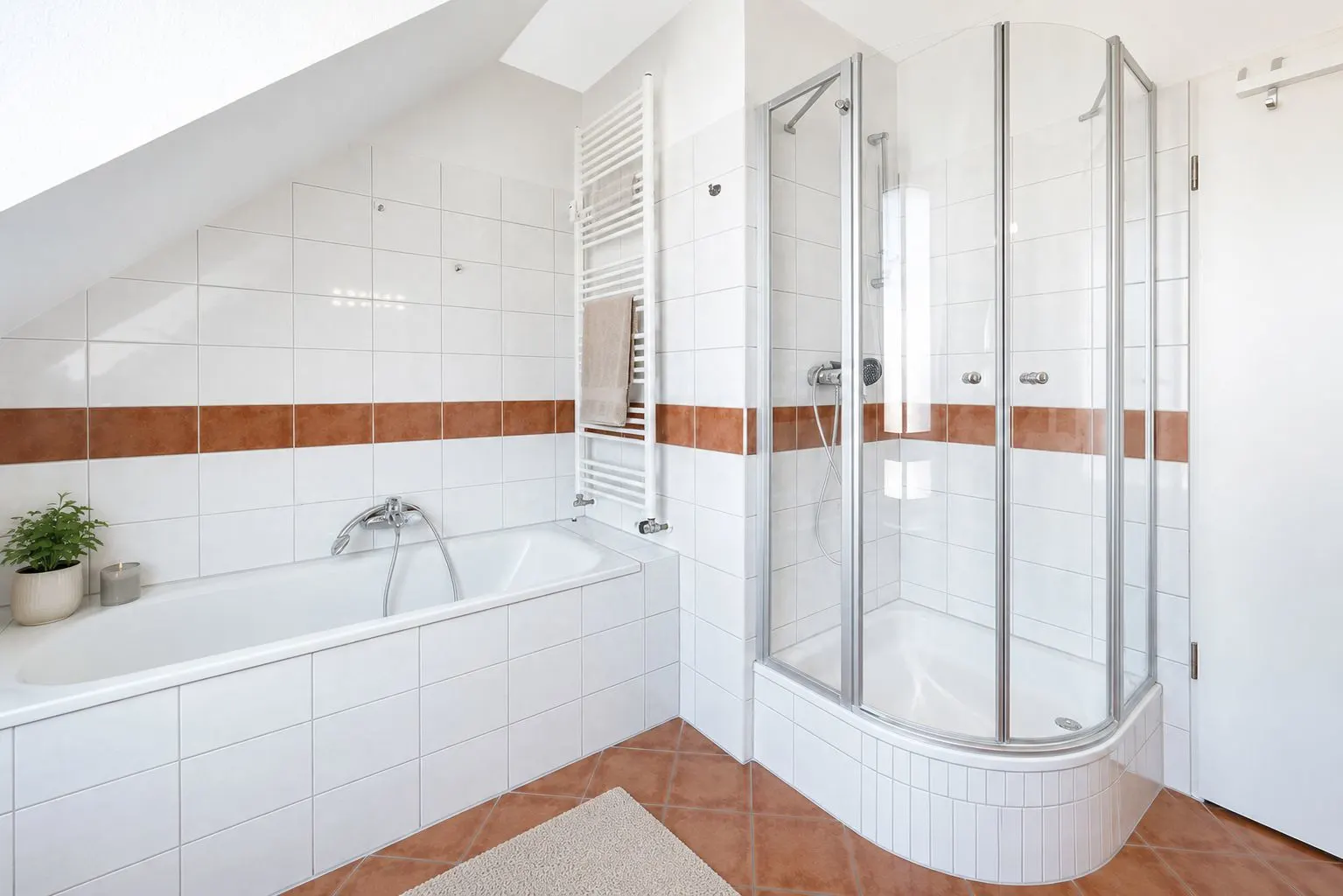Modernes Badezimmer mit Badewanne, Dusche und weißen Fliesen mit brauner Zierleiste.