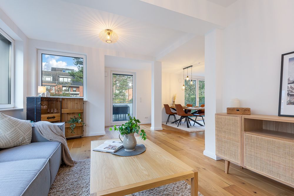 Helles Wohnzimmer mit Holzboden, Sofa, Holztisch und Blick auf den Essbereich.
