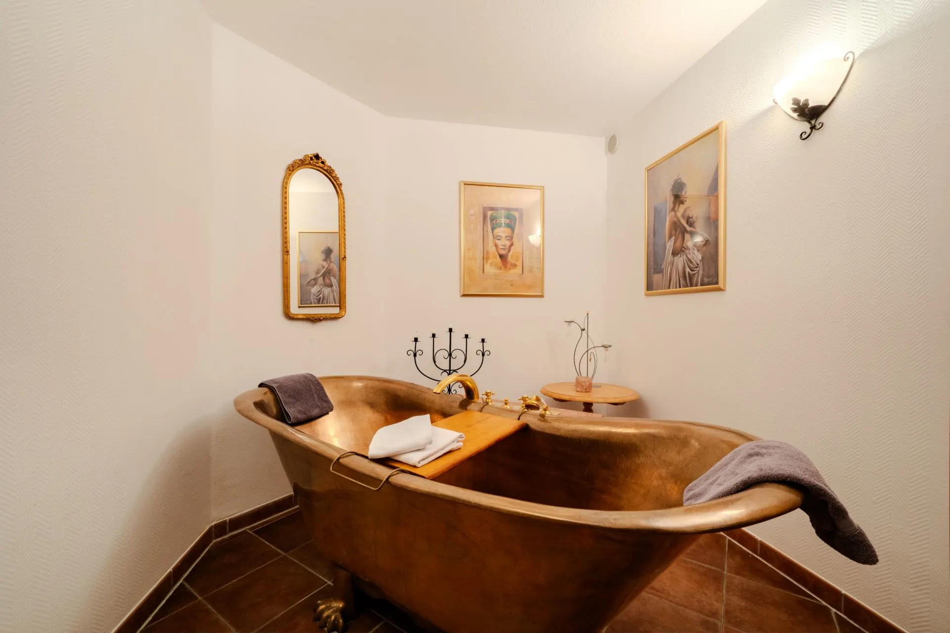 Kupferfarbene Badewanne in einem Badezimmer mit Kunstwerken an den Wänden.