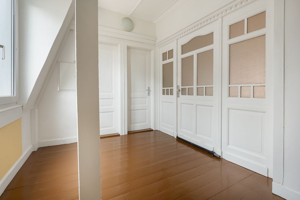 Heller Flur mit weiß gestrichenen Türen und braunem Holzboden.