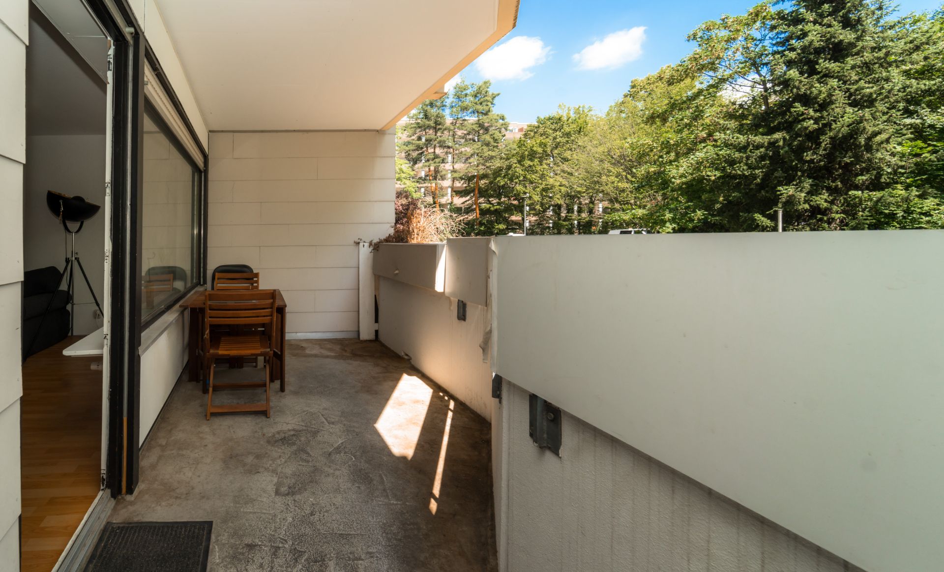 Balkon mit Holztisch und zwei Stühlen, Blick ins Grüne.