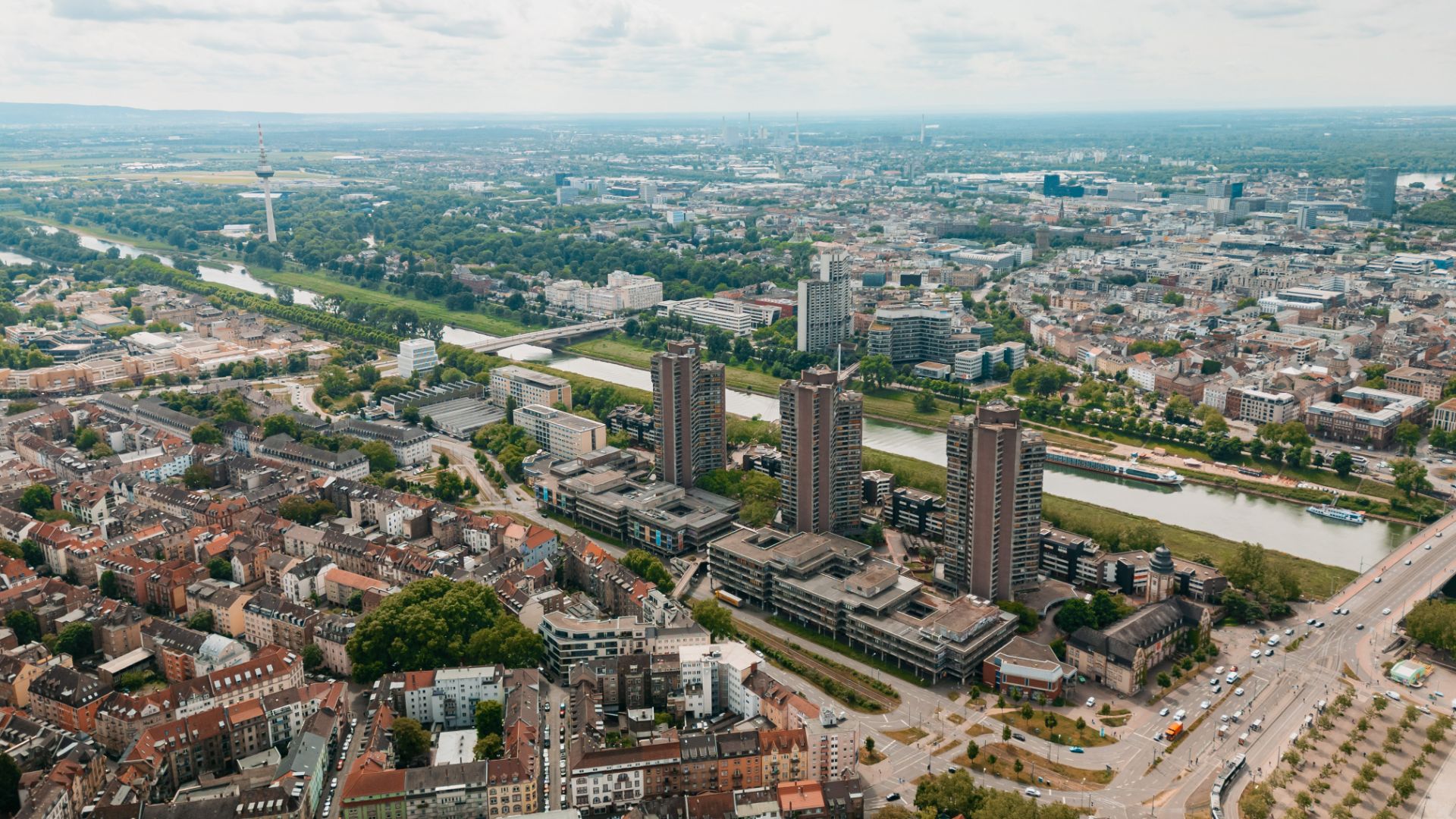 Luftaufnahme einer Stadt mit Fluss, Hochhäusern und vielen Wohngebäuden.