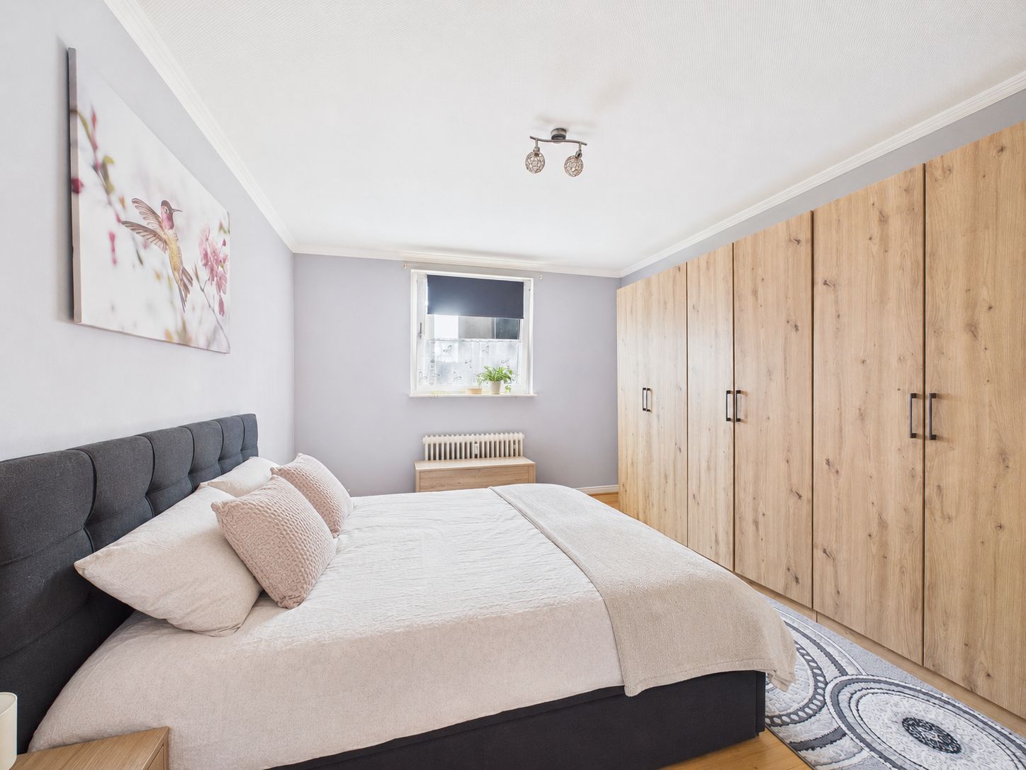 Helles Schlafzimmer mit Doppelbett, großem Holzkleiderschrank und Fenster.