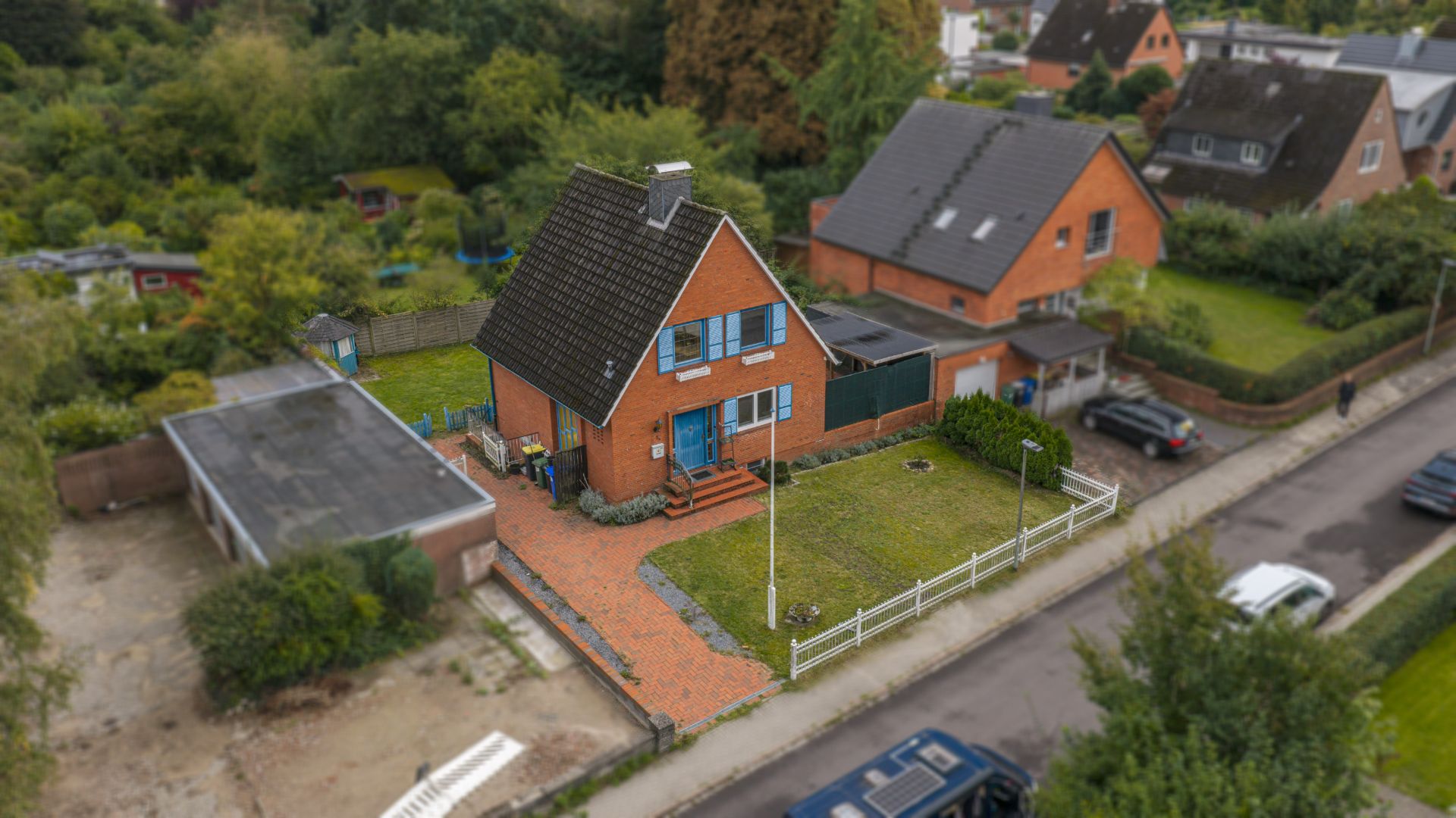 Backsteinhaus mit Garten, Eingangsweg und angrenzender Garage an einer Wohnstraße.