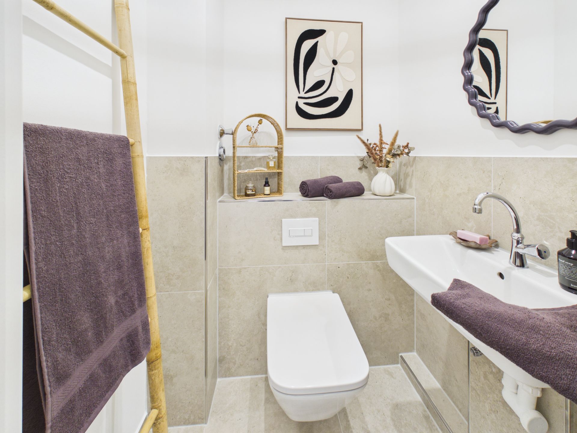 Modernes Badezimmer mit WC, Waschbecken, Spiegel und Handtüchern, Kunst an der Wand.