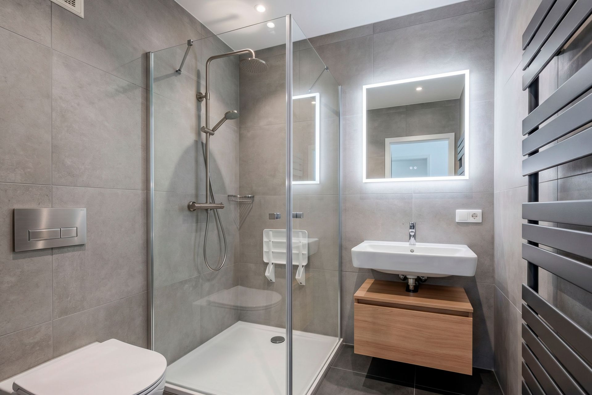 Modernes Badezimmer mit Glasdusche, beleuchtetem Spiegel und Waschbecken mit Holzunterschrank.