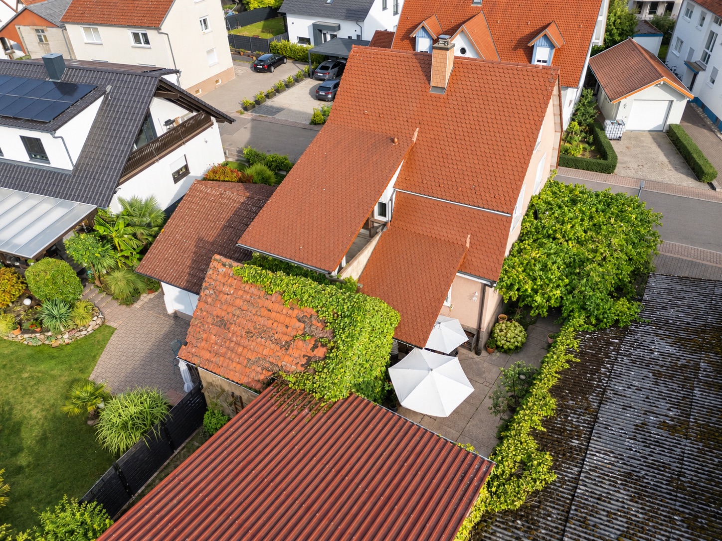 Luftaufnahme von Wohnhäusern mit roten Dächern und grünem Garten.