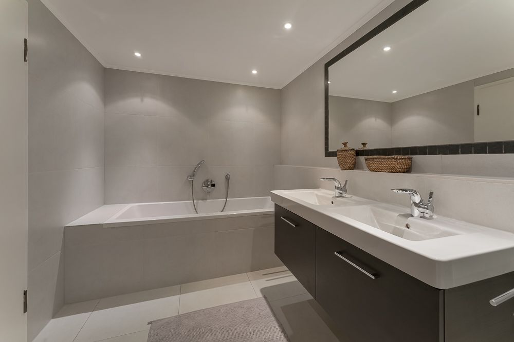 Modernes Badezimmer mit Badewanne, zwei Waschbecken und großem Spiegel.