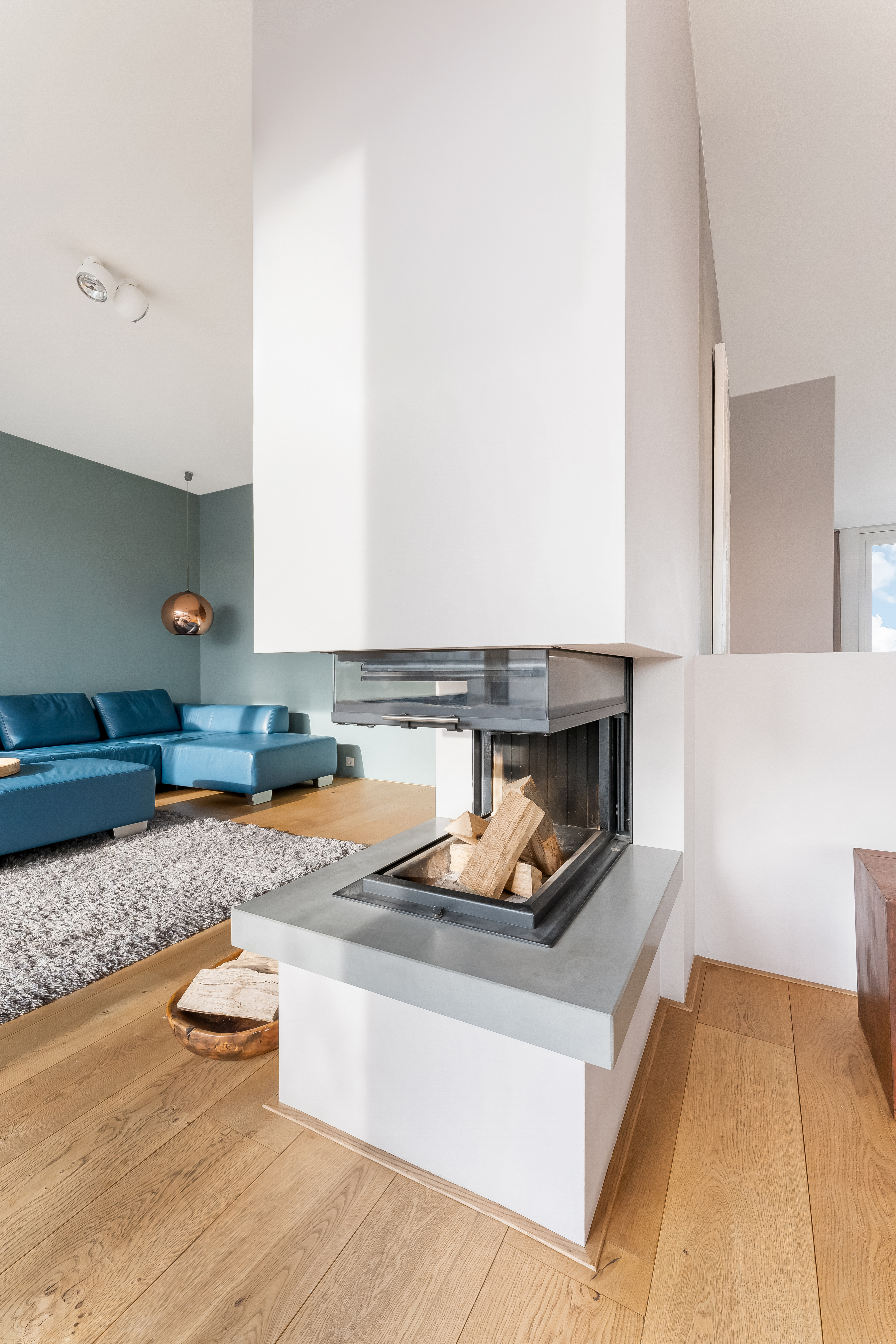 Modernes Wohnzimmer mit Ecksofa, Kamin und Holzboden.
