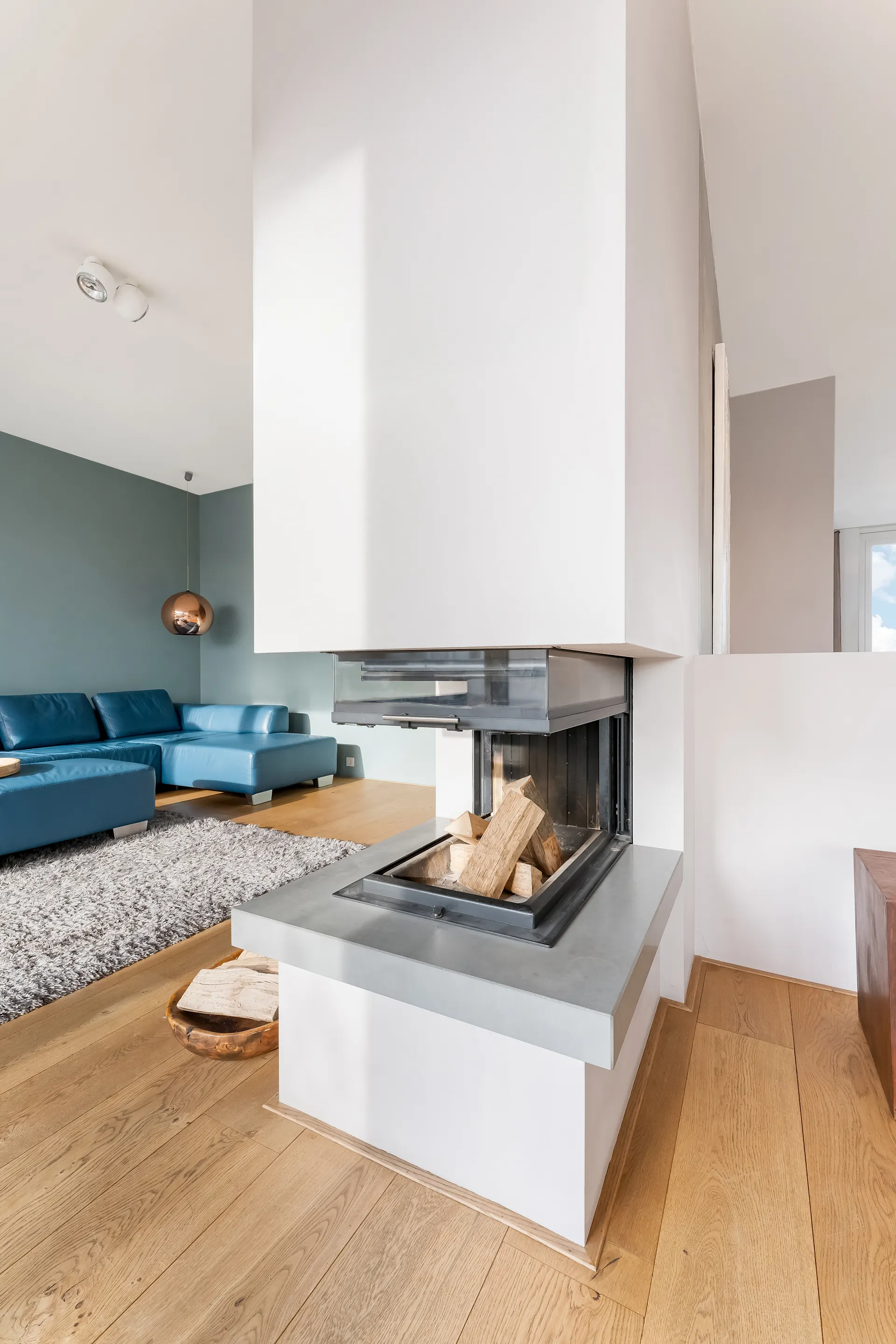 Modernes Wohnzimmer mit Ecksofa, Kamin und Holzboden.