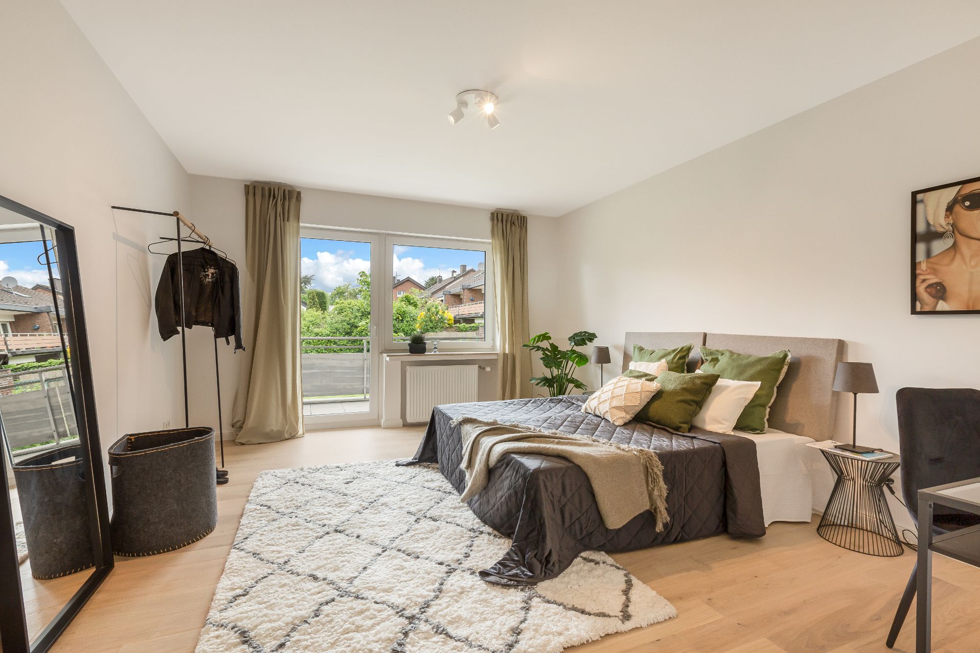 Modernes Schlafzimmer mit Doppelbett, großen Fenstern, Teppich und Pflanzen.