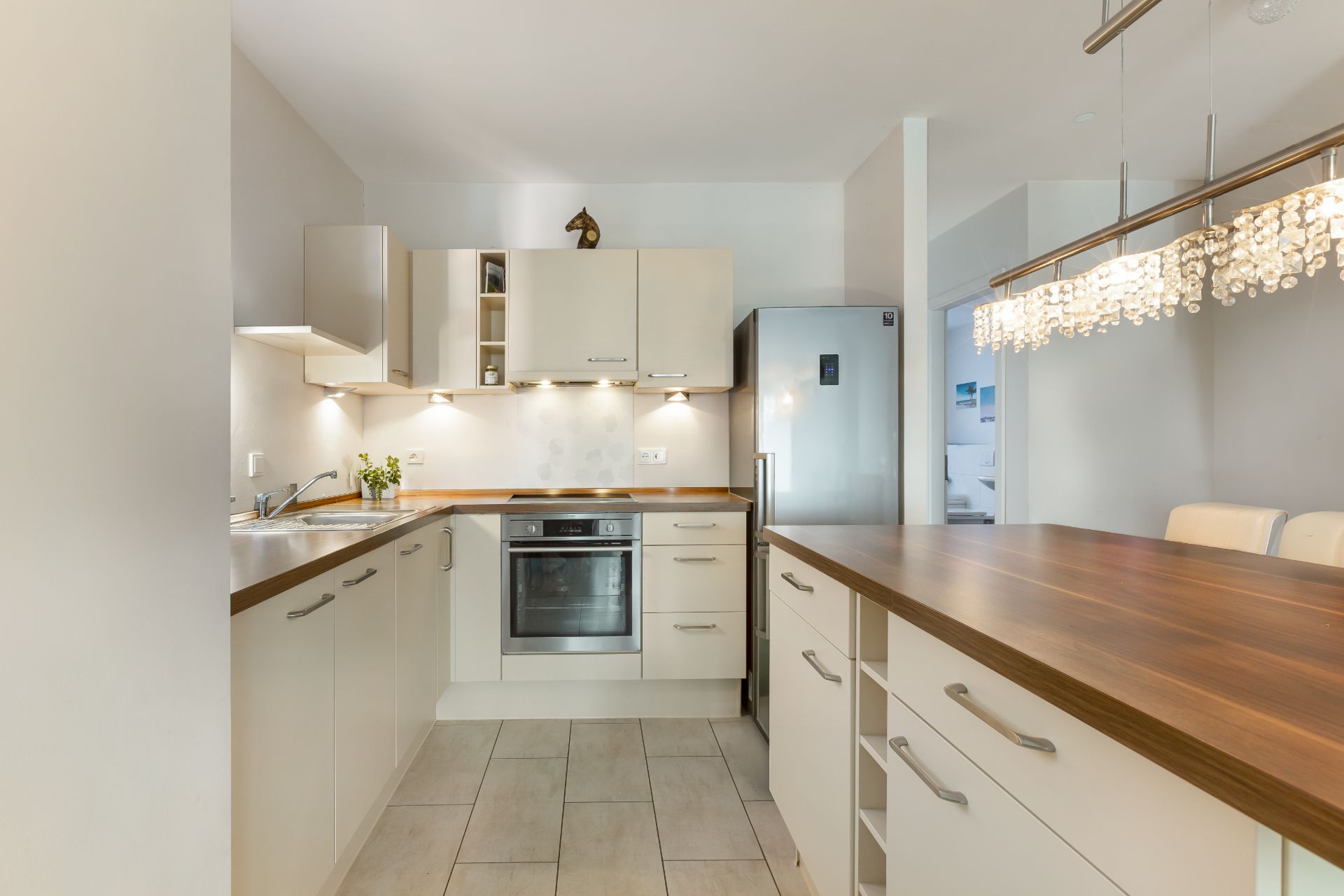 Moderne Einbauküche mit Holzarbeitsplatten, Herd, Spüle und Kühlschrank.