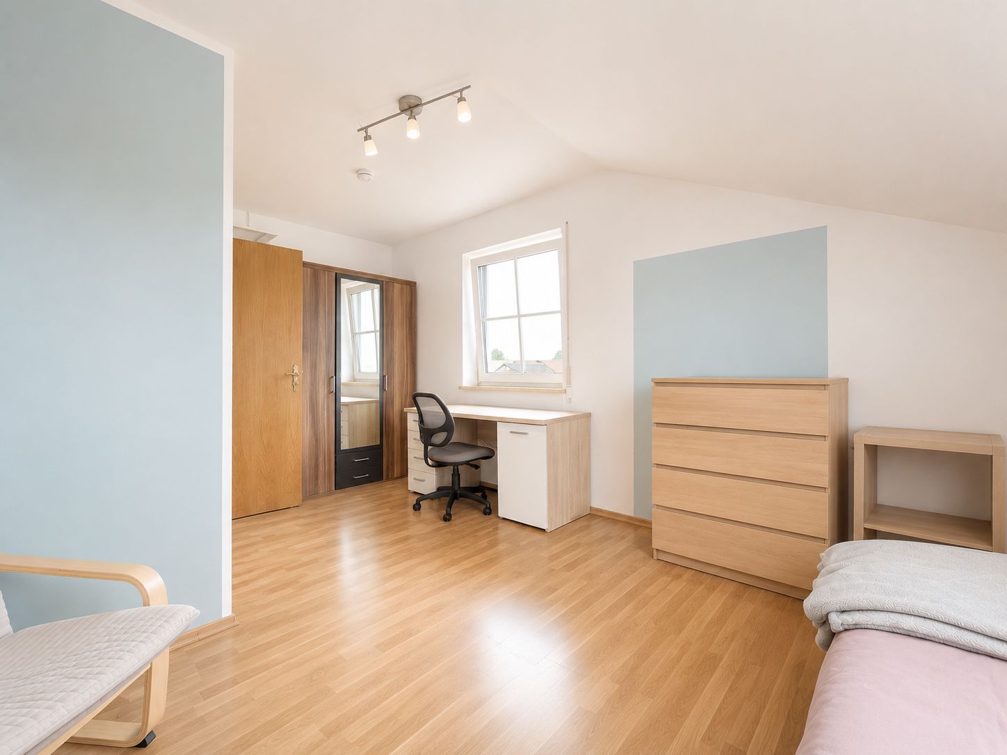 Helles Schlafzimmer mit Schreibtisch, Stuhl, Kommode, Kleiderschrank und Einzelbett.