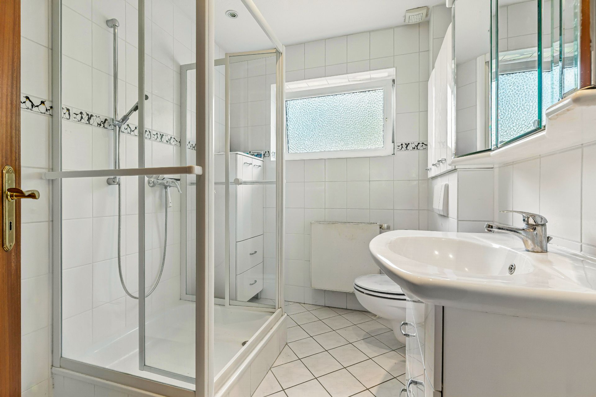 Helles Badezimmer mit Dusche, Waschbecken, Toilette und Spiegelschrank.