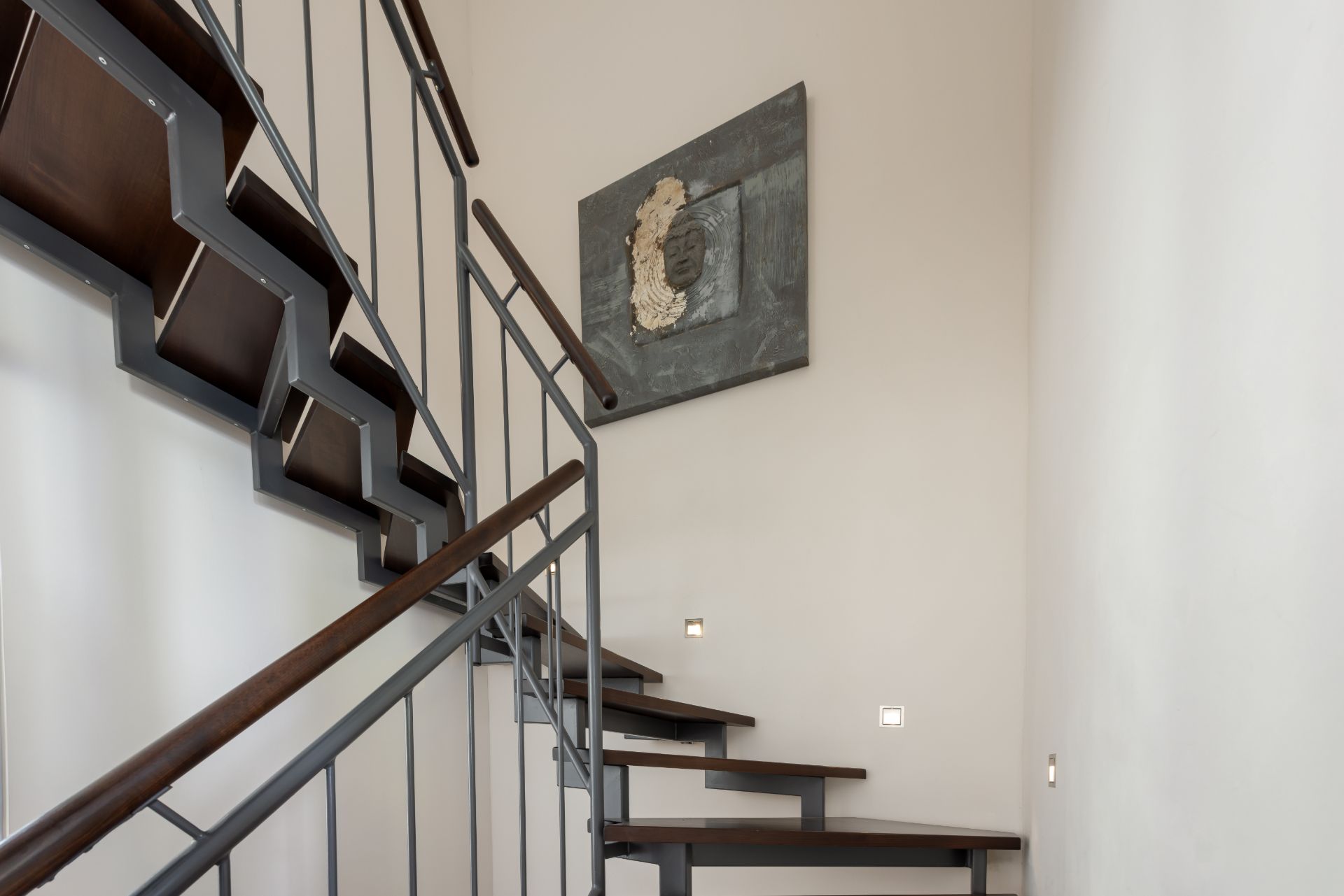 Moderne Wendeltreppe mit Metallgeländer und Wandbild in einem Wohnhaus.