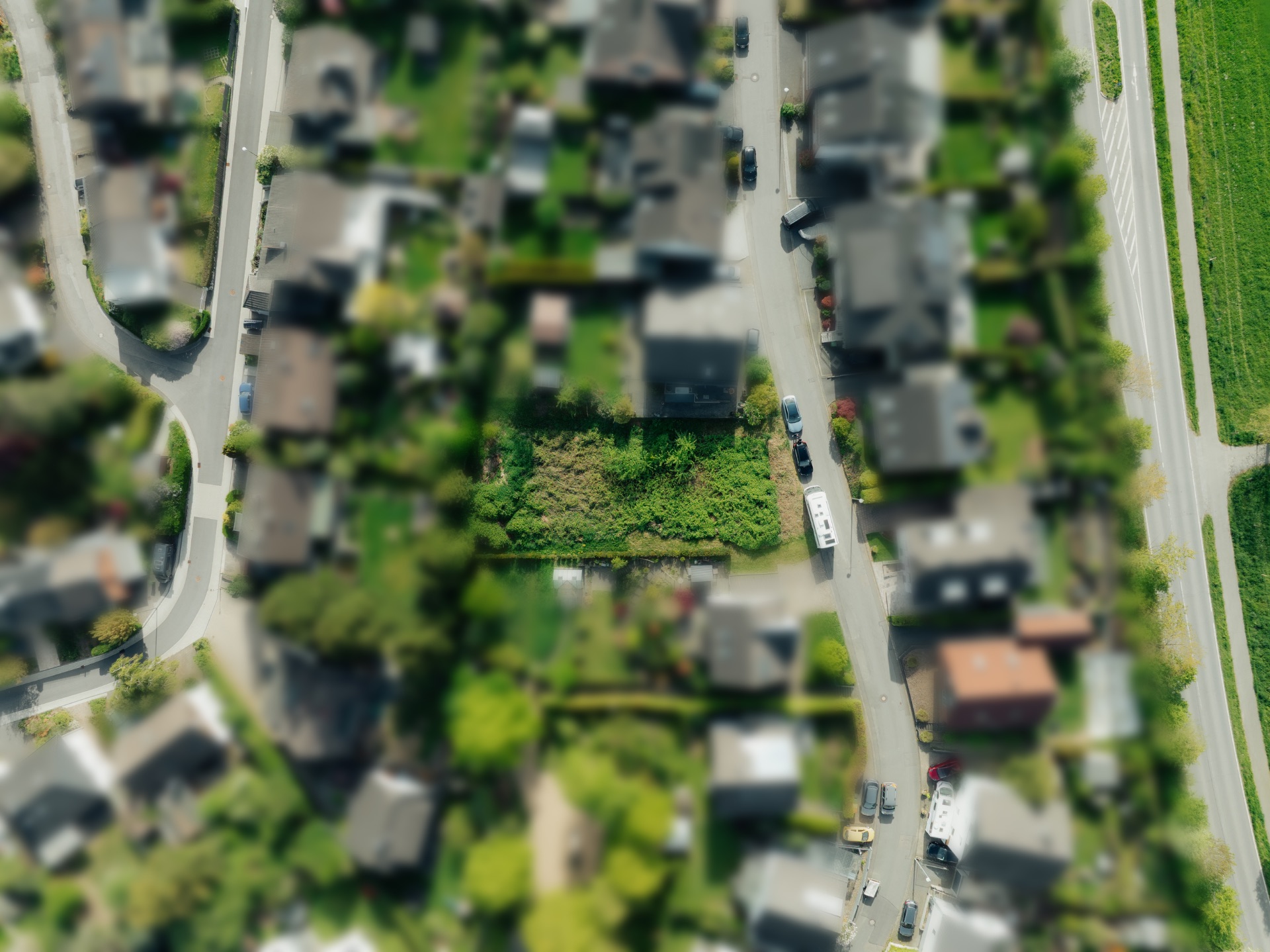 Luftaufnahme eines Wohngebiets mit Häusern, Straßen und viel Grünfläche.