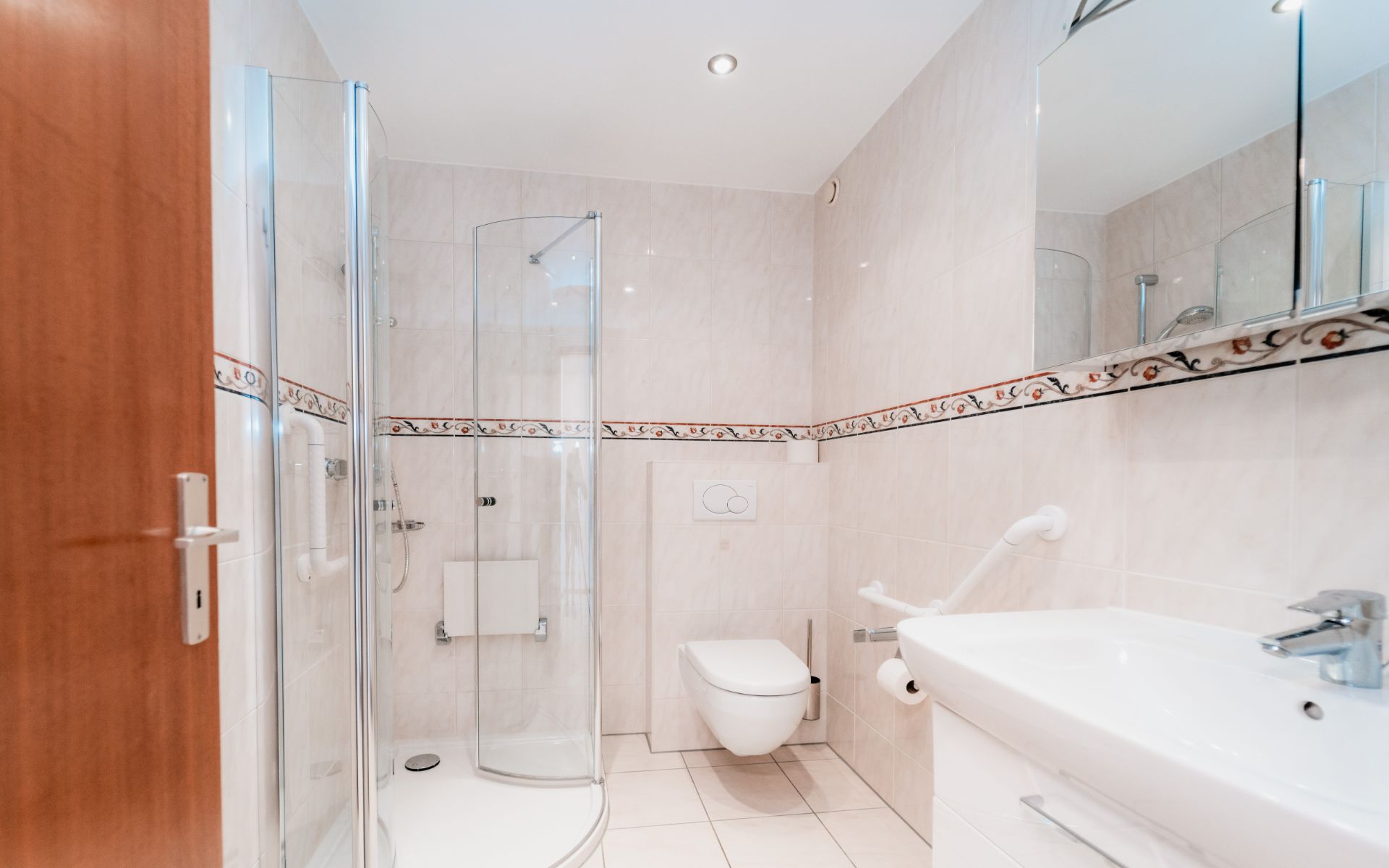 Modernes Badezimmer mit Dusche, WC, Waschbecken und großem Spiegel.