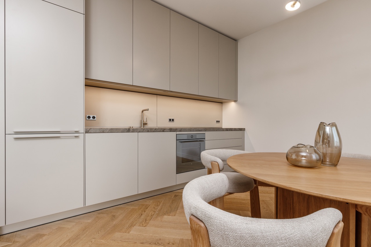 Moderne Küche mit Einbauschränken, Esstisch und vier Stühlen auf Holzfußboden.