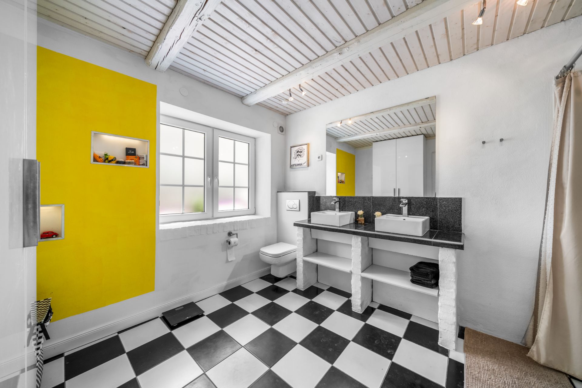 Modernes Badezimmer mit schwarz-weißem Fliesenboden, gelber Wand, Doppelwaschtisch und Fenster.