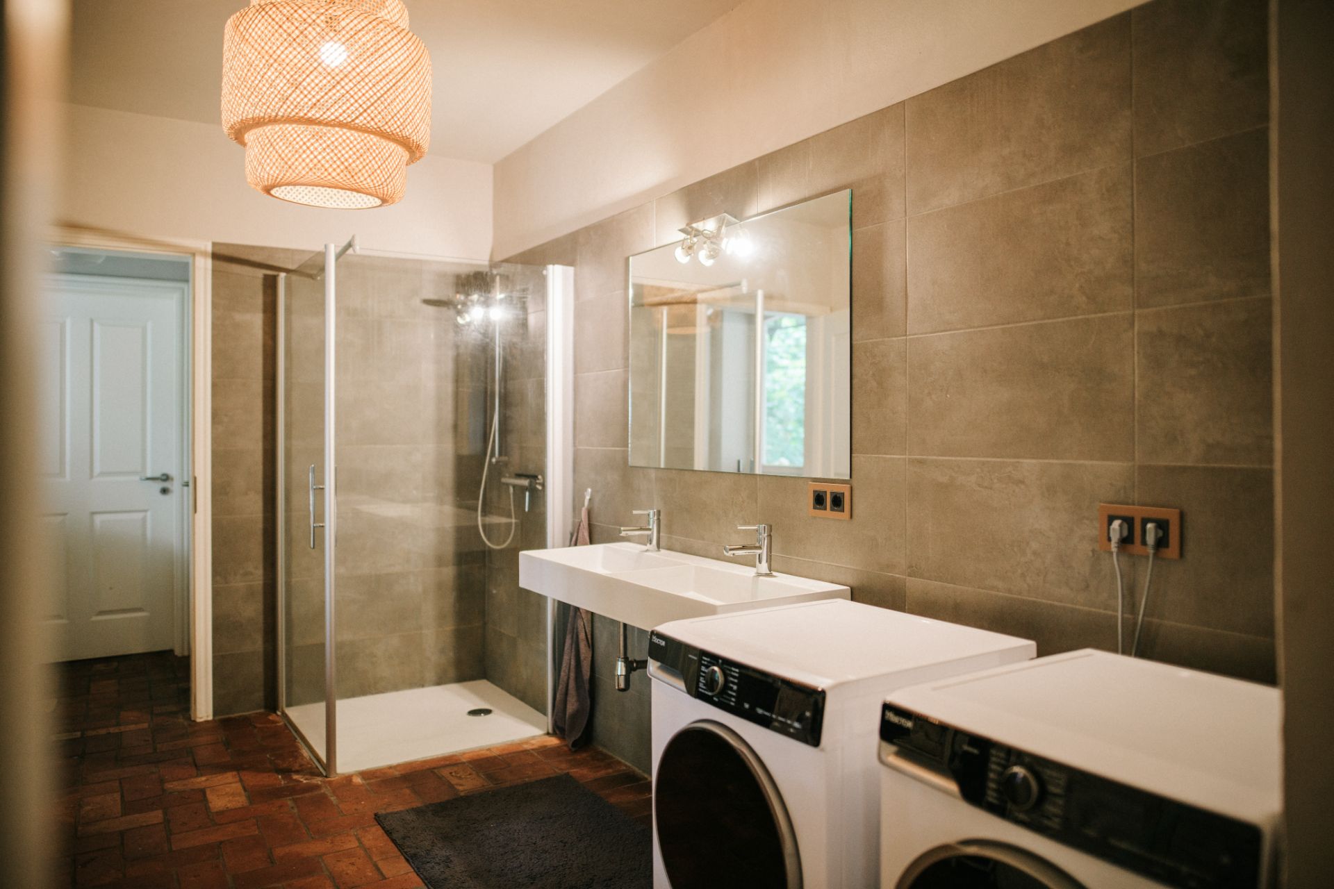 Modernes Badezimmer mit Doppelwaschbecken, Dusche, Waschmaschine und Trockner.