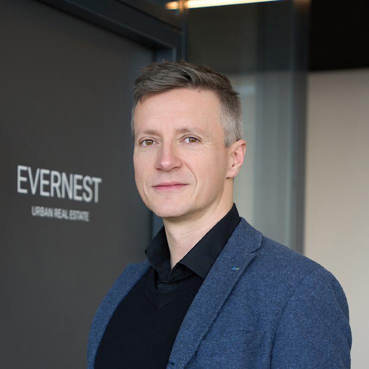 Ein Mann steht vor einer Tür mit der Aufschrift 'EVERNEST URBAN REAL ESTATE'.