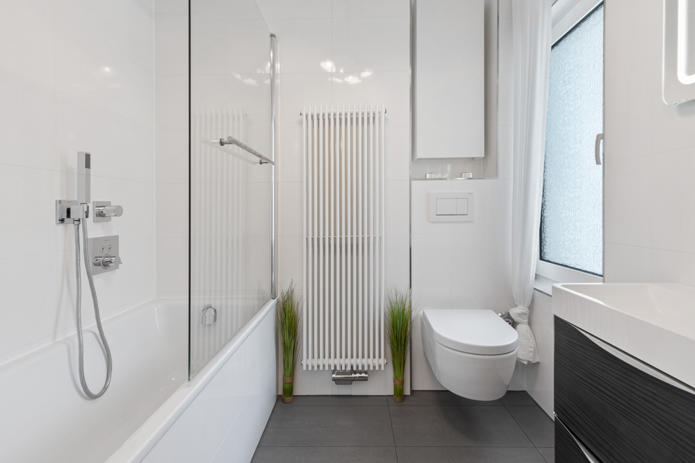 Modernes Badezimmer mit Badewanne, wandhängender Toilette, Waschbecken und großem Fenster.