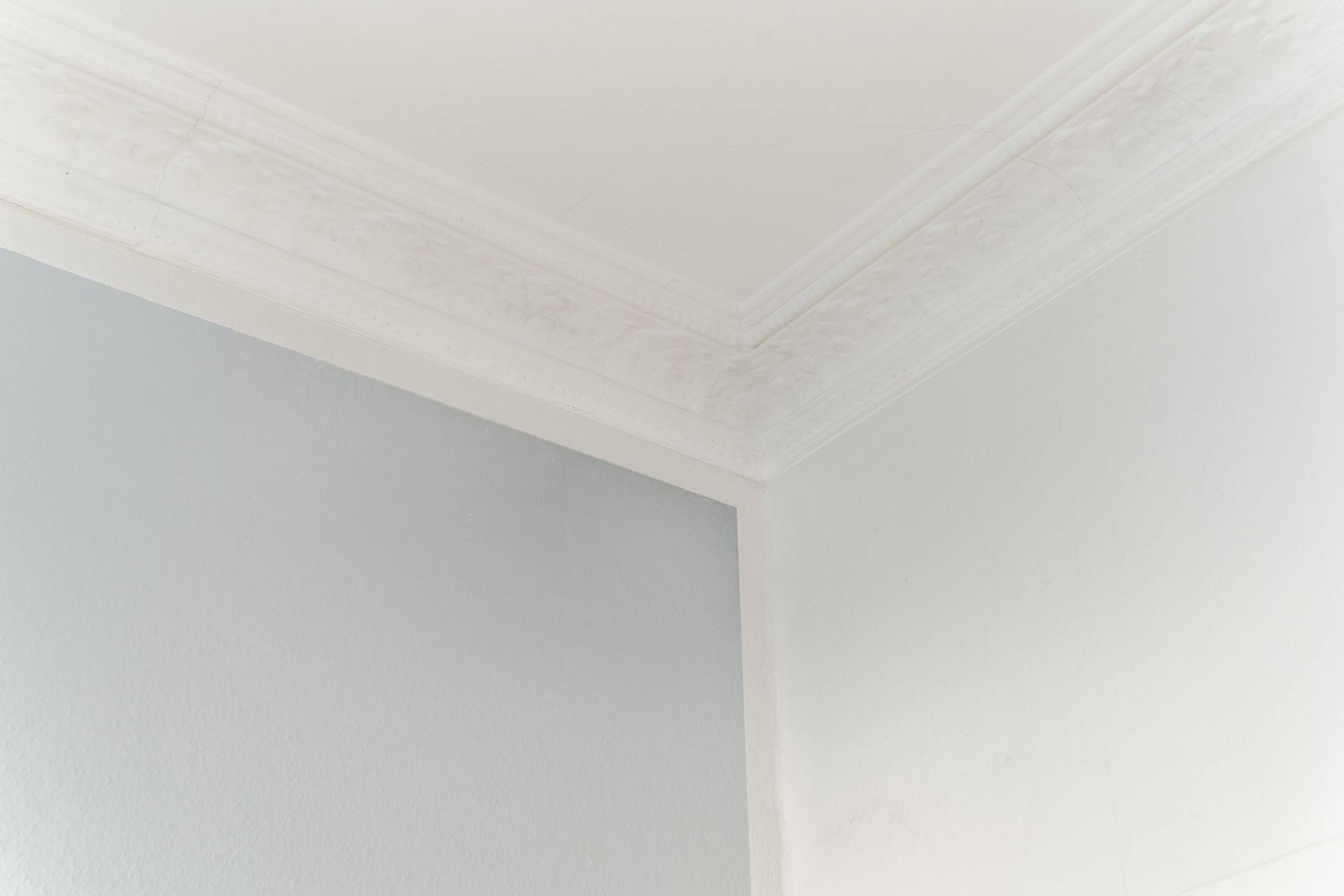 Ecke eines Raumes mit weißer Stuckverzierung an der Decke.