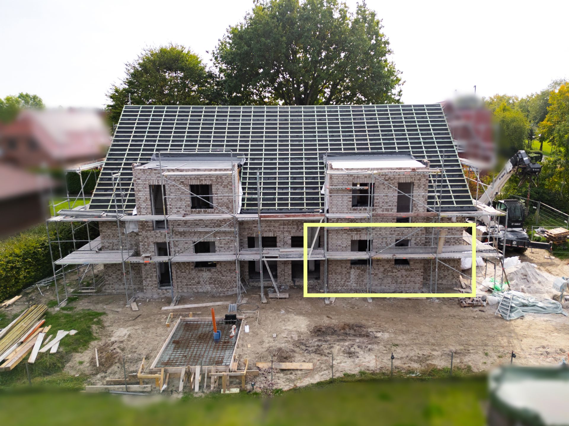 Ein zweistöckiges Wohnhaus im Bau mit Gerüst und großem Dach.