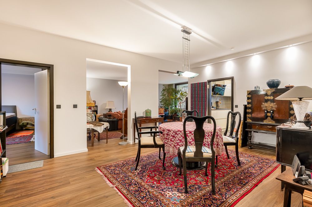 Esszimmer mit Teppich, Tisch, Stühlen und Blick in Wohnzimmer sowie Schlafzimmer.
