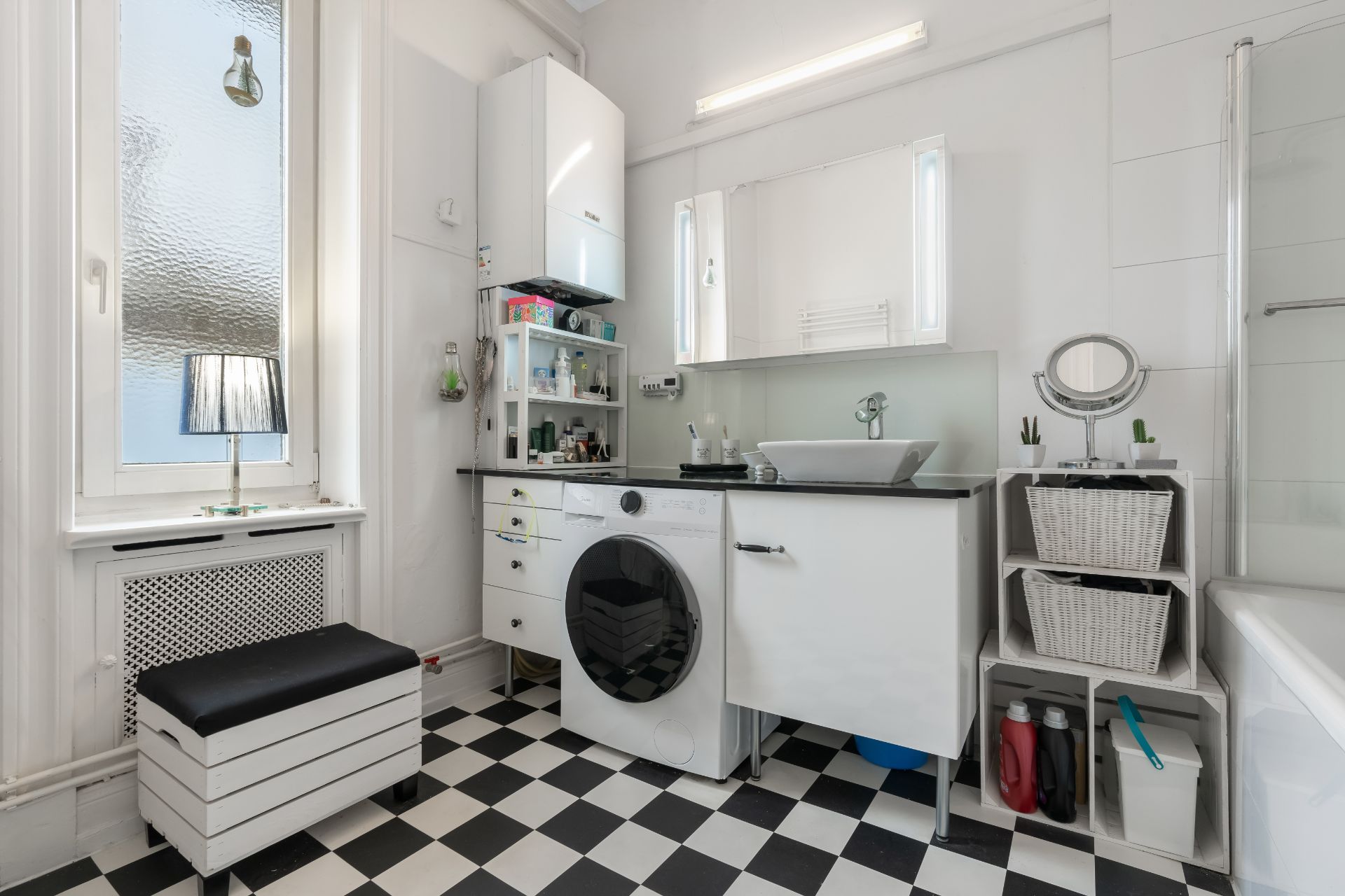 Modernes Badezimmer mit Waschmaschine, Waschbecken, Spiegel und Schachbrett-Fliesenboden.