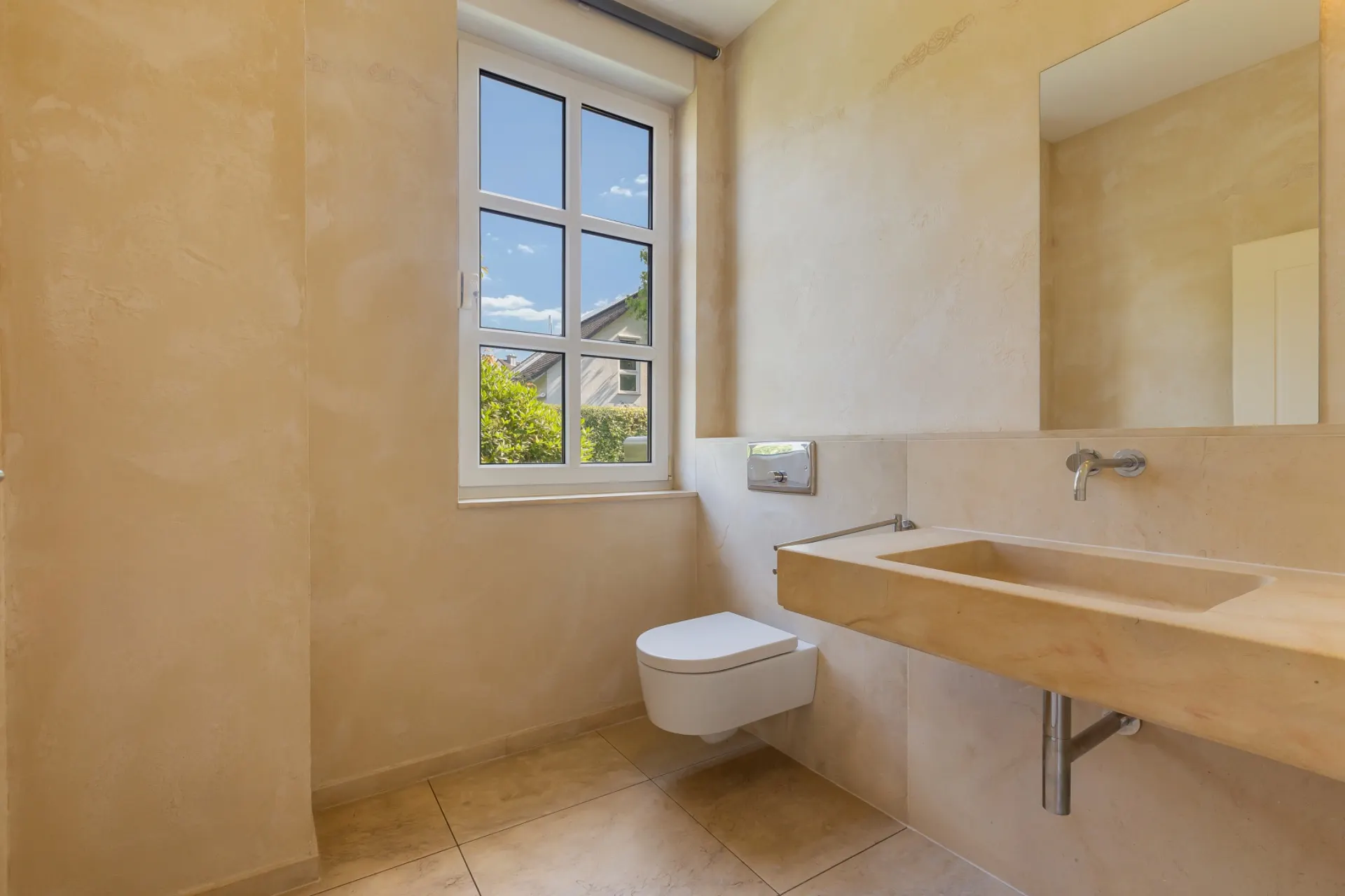 Modernes Bad mit großem Fenster, Wandtoilette und rechteckigem Waschbecken aus Stein.