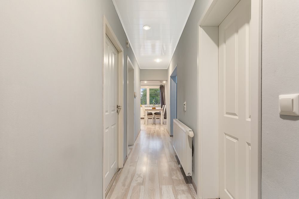 Heller Flur mit mehreren Türen und Blick auf einen Esstisch am Ende des Gangs.
