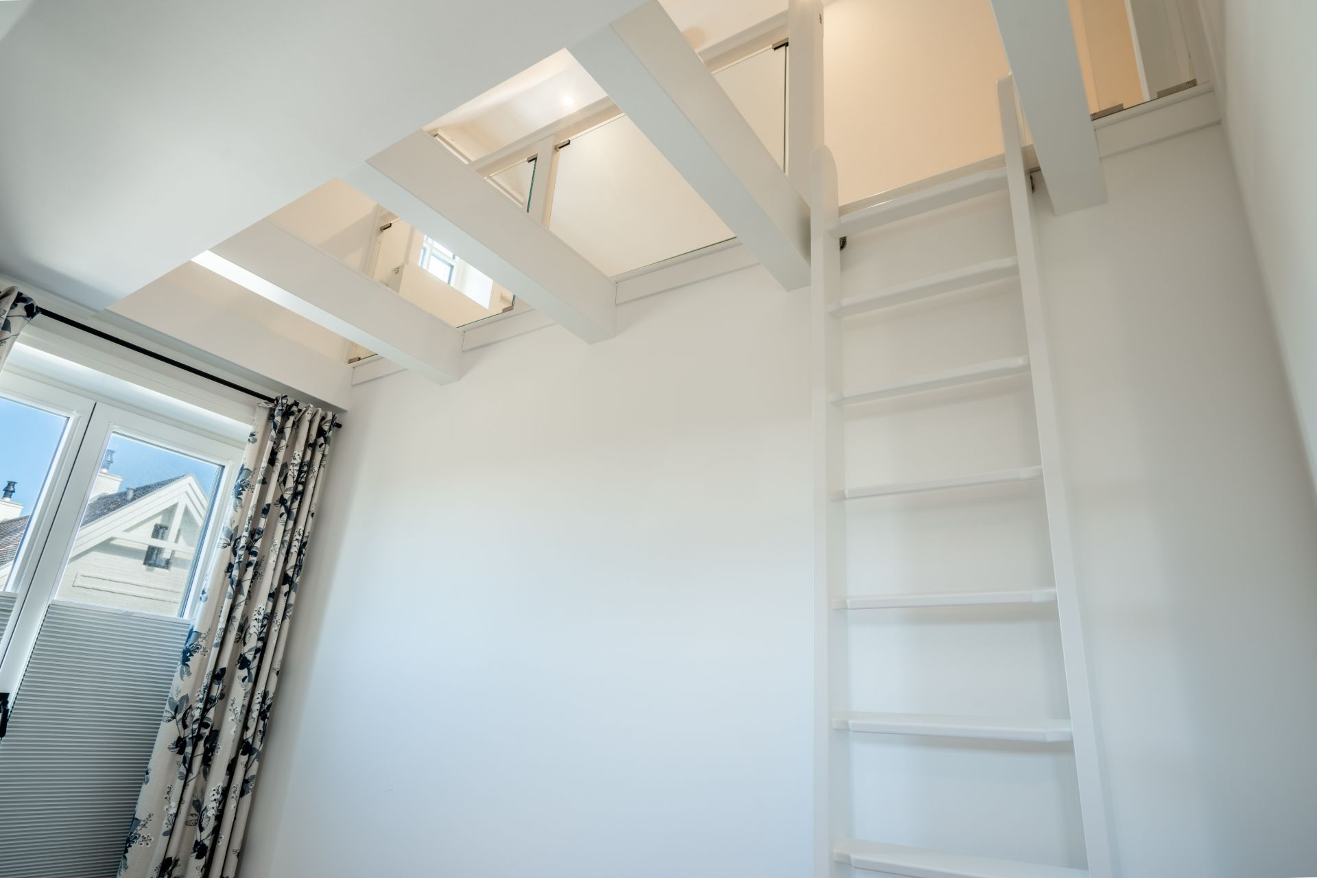 Heller Raum mit Fenster, Leiter und offener Galerie unter der Decke.