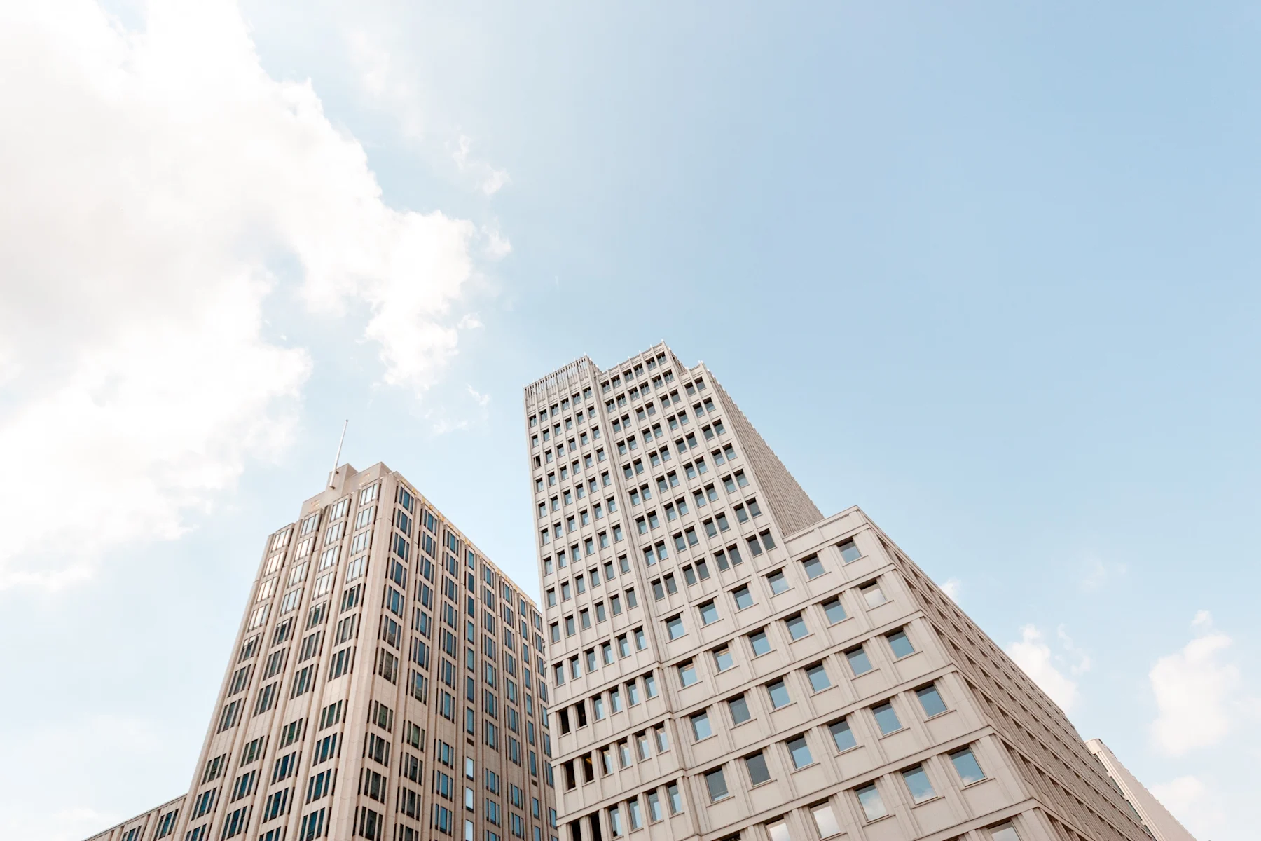 Mehrere moderne Wohngebäude mit vielen Fenstern vor blauem Himmel.