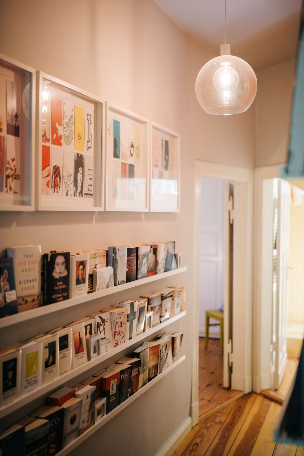 Flur mit Bücherregalen an der Wand und mehreren gerahmten Bildern darüber.
