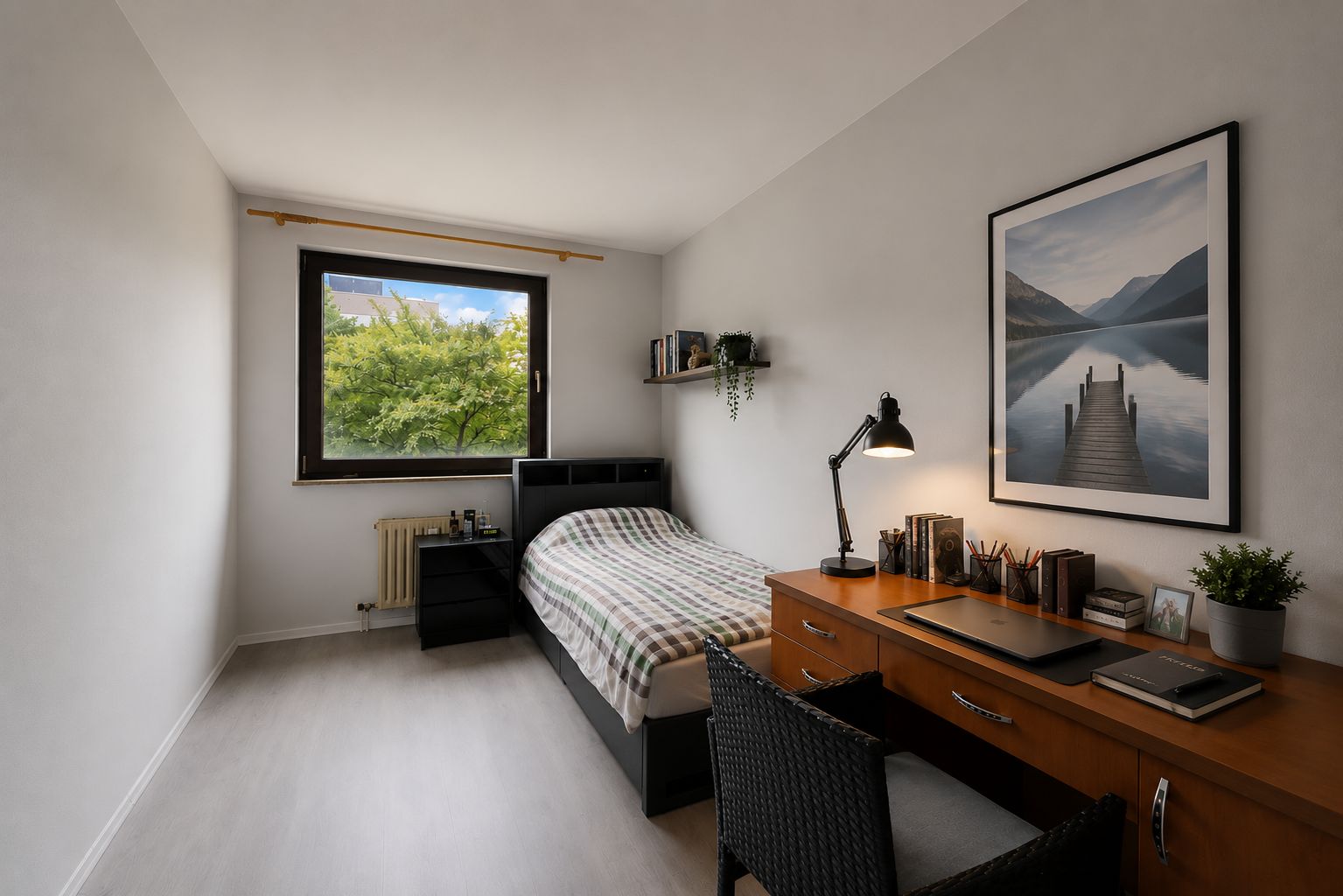 Kleines Schlafzimmer mit Einzelbett, Schreibtisch, Stuhl und Fenster mit Blick ins Grüne.