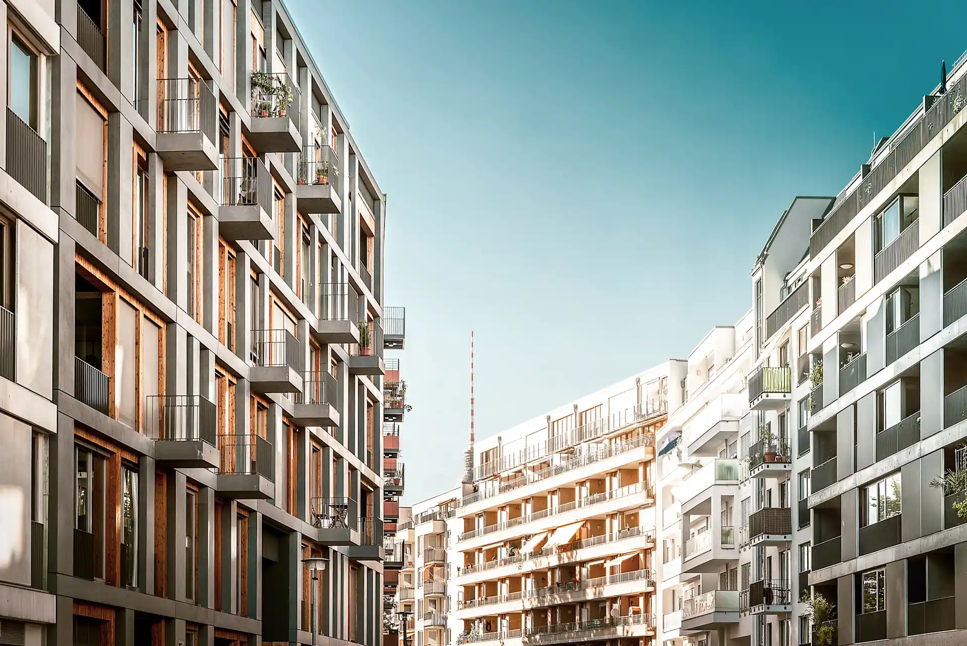 Moderne Wohngebäude mit Balkonen an einer Straße bei klarem Himmel.