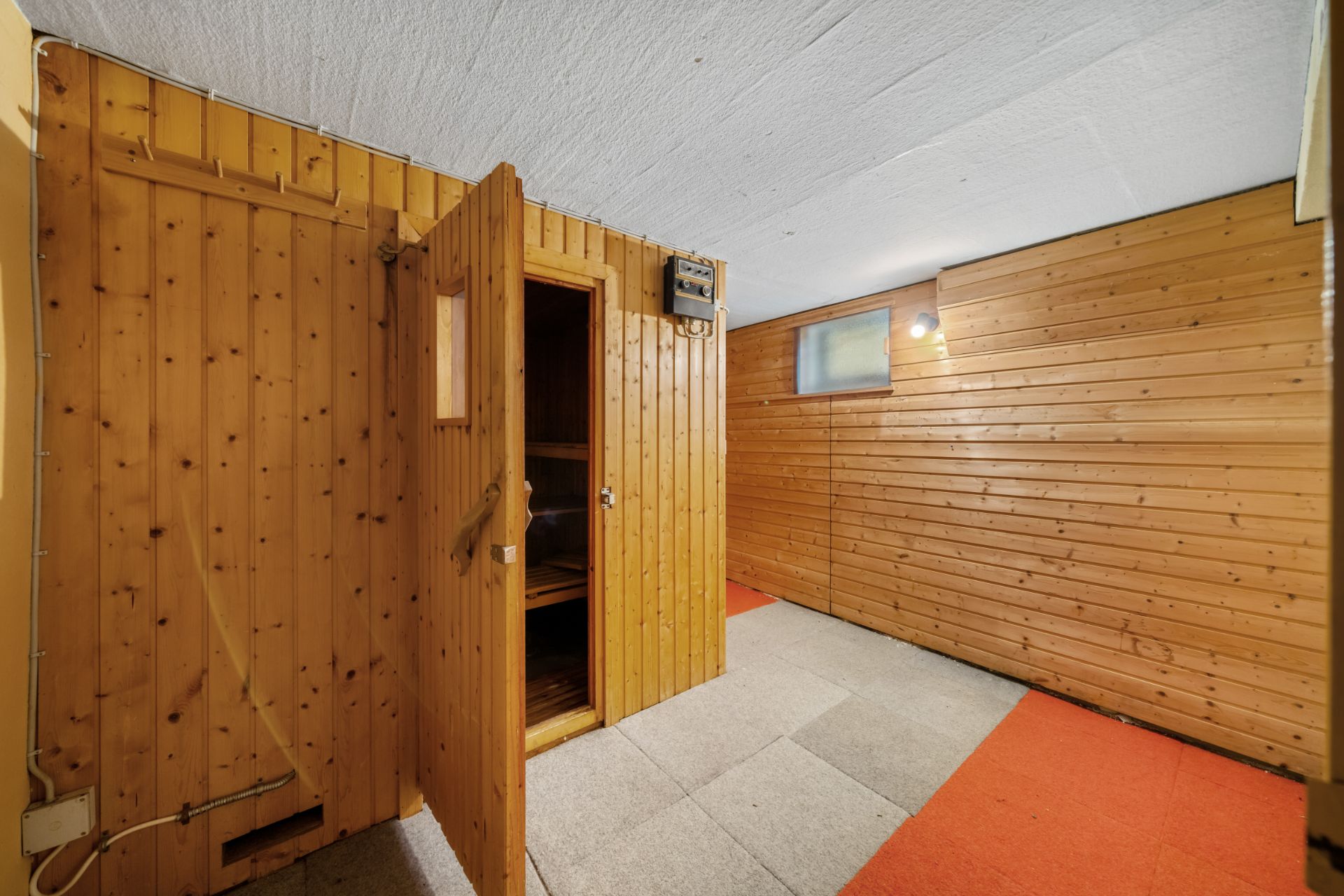 Kellerraum mit Holzverkleidung und einer offenen Sauna aus Holz.